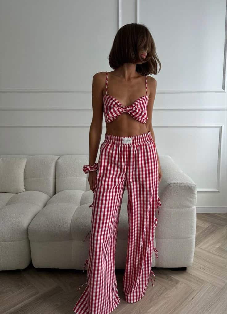 Woman in red plaid two-piece outfit standing in a modern room with white sofa and wooden floor.