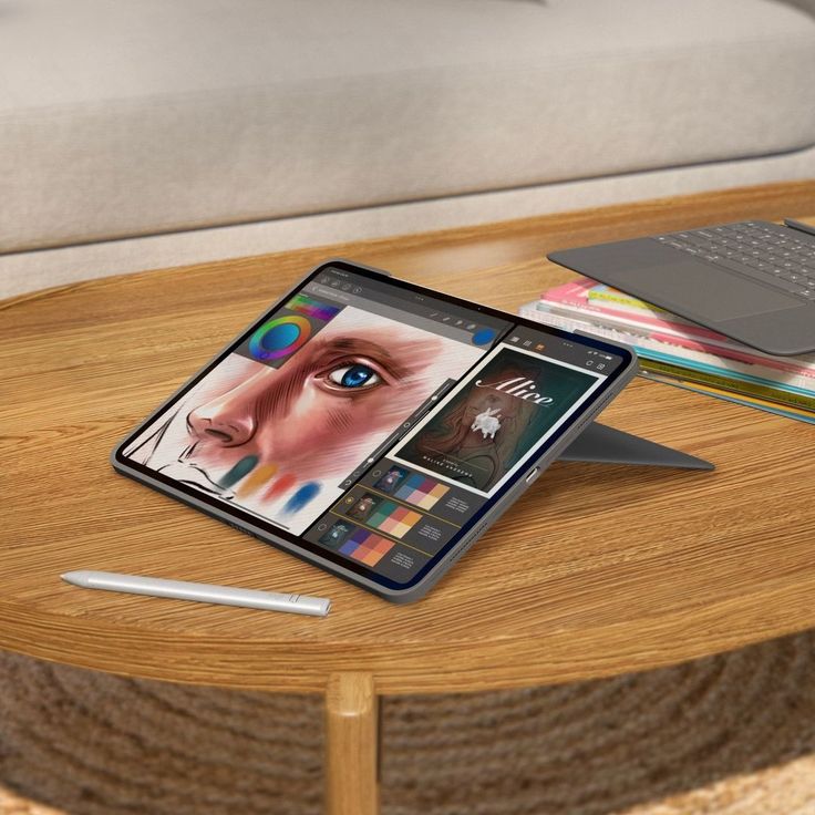 Tablet displaying digital art and design on a wooden table, stylus nearby, in a cozy home setting.