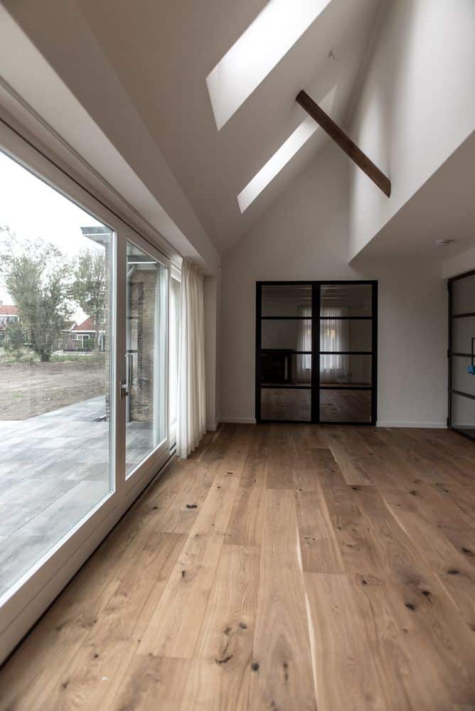 © Marc de fotograaf Modern room with wooden flooring, skylights, and large windows opening to a backyard with greenery. | Sky Rye Design Modern room with wooden flooring, skylights, and large windows opening to a backyard with greenery.