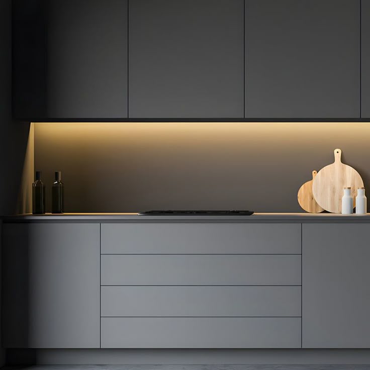 Modern kitchen with sleek gray cabinets, under-cabinet lighting, and wooden cutting boards for a minimalist look.