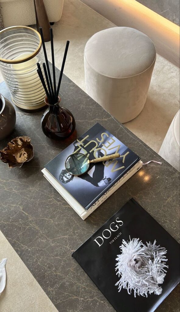Stylish coffee table with decorative books, magnifying glass, and elegant accessories in a modern living room setting.