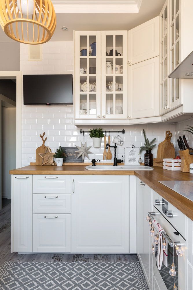 76c6faa9a53489f440ae6d821dff0010 Bright kitchen with white cabinets, wood countertops, and modern decor, featuring a wall-mounted TV and glass cupboards. | Sky Rye Design Bright kitchen with white cabinets, wood countertops, and modern decor, featuring a wall-mounted TV and glass cupboards.