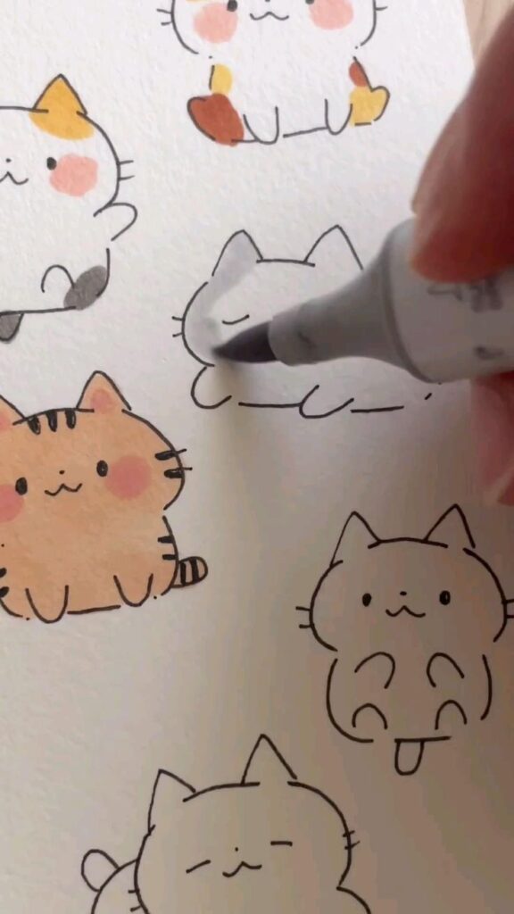 Drawing cute cartoon cats with colored markers on paper.