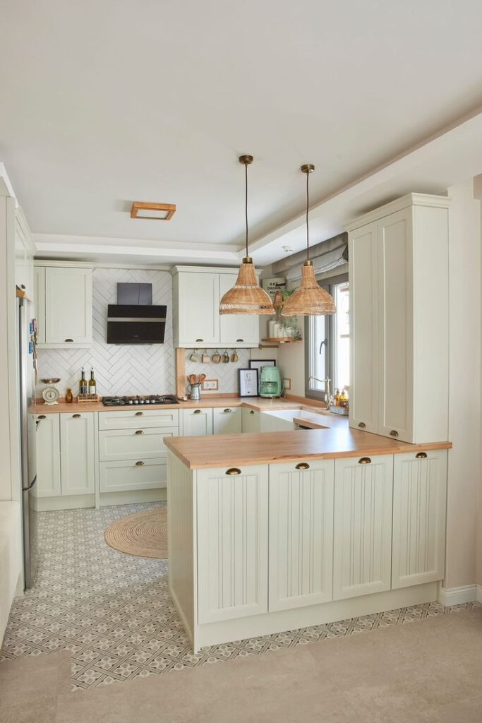 Elegant kitchen with light green cabinets, wood countertops, and pendant lighting. Cozy and stylish cooking space.