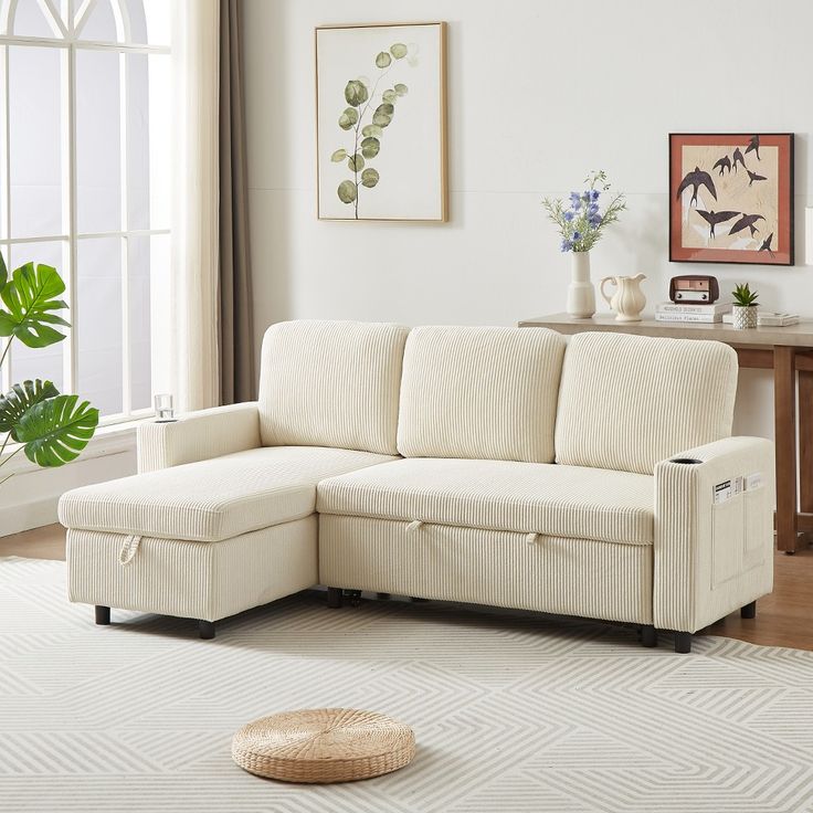 78_7_ Corduroy_Linen Upholstered L-Shaped Sleeper Sofa with Pullout Bed Storage Space Cup Holders and Side Pocket Beige 4L -ModernLuxe Cream-colored sectional sofa in a bright living room with decorative plants and wall art. | Sky Rye Design Cream-colored sectional sofa in a bright living room with decorative plants and wall art.