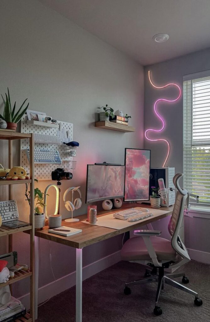 Modern home office setup with dual monitors, pink neon lights, and plants on a wooden desk and shelves by the window.