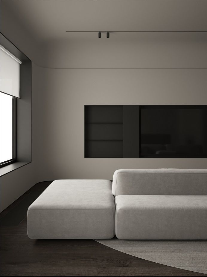 Modern minimalist living room with a gray sofa, dark flooring, and neutral walls. Elegant and serene interior design.