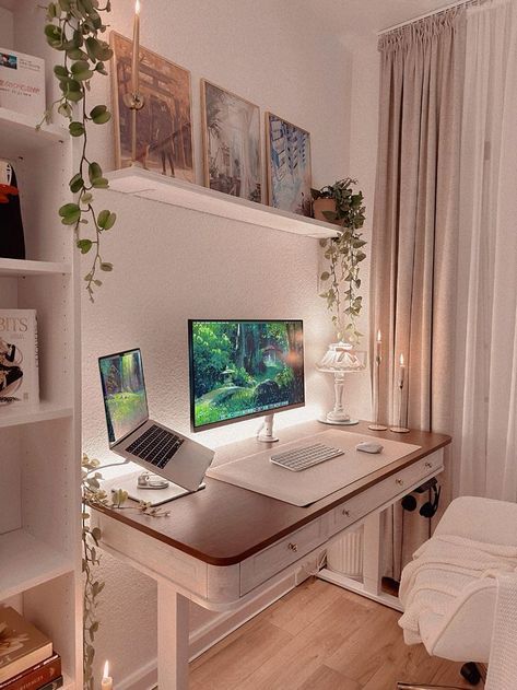Cozy home office with a wooden desk, laptop, monitor, plants, and candles for a warm, inviting workspace ambiance.