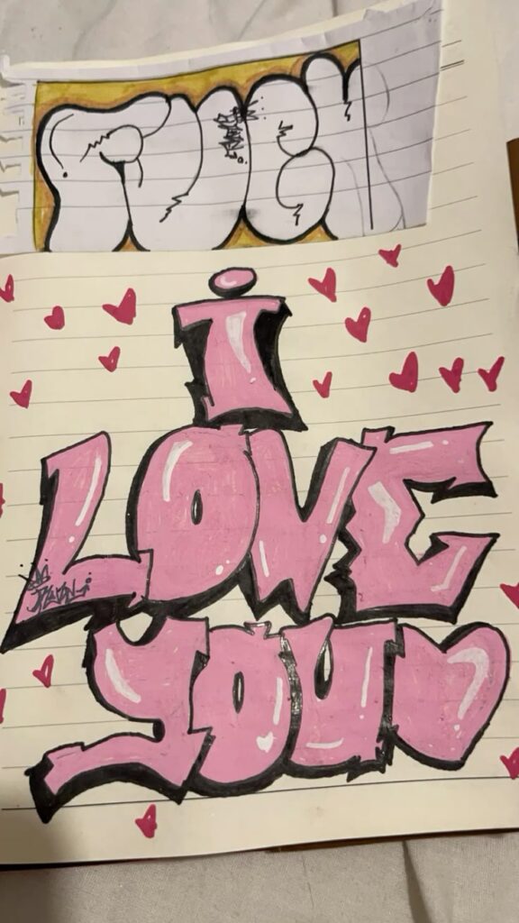 Graffiti art with I Love You in pink and white letters, surrounded by pink hearts on lined paper.