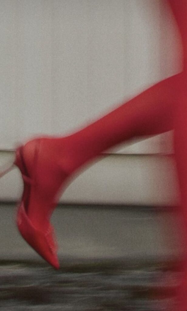 Red high heel in motion, capturing dynamic style and elegance against a blurred background.