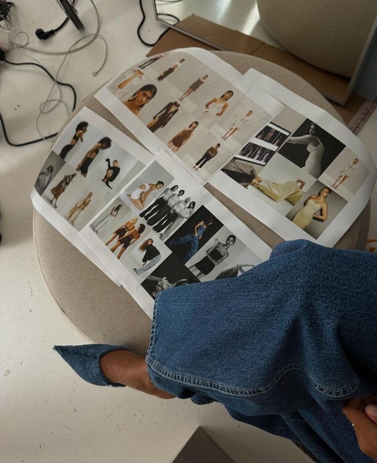 Fashion mood board with model photos on a beige chair, denim-clad person nearby, creative workspace.