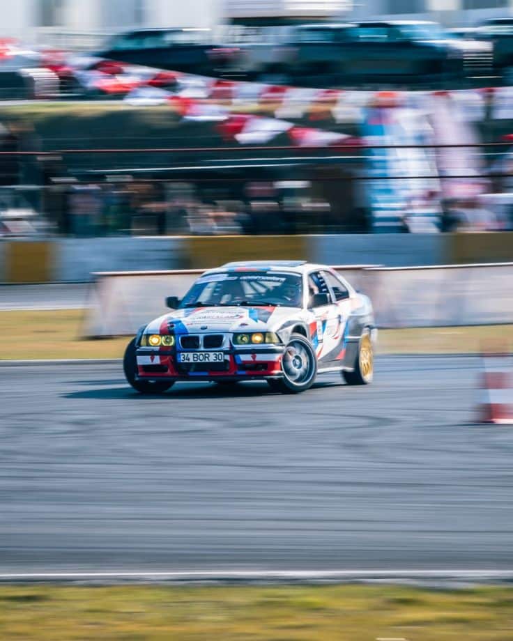 Race car drifting on track, showcasing speed and precision during a motorsport event with blurred motion effect.