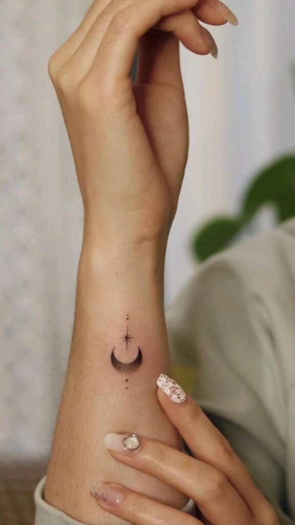 Minimalist moon and star wrist tattoo with elegant nail art.