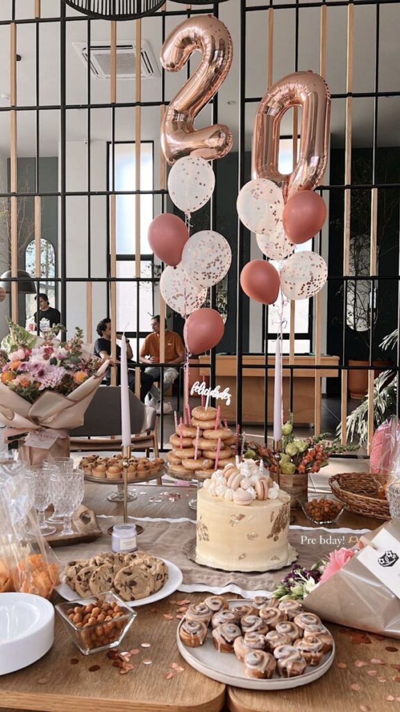 Birthday celebration with cake, donuts, balloons, and flowers for a 20th birthday party setup on a decorated table.