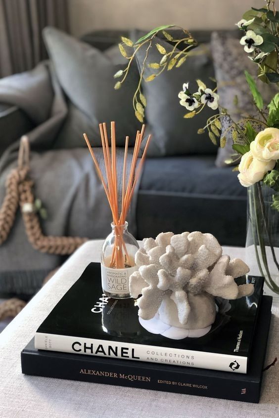8c9a5efe-1d6a-4d62-9b70-58a43442992a Elegant living room decor with Chanel and Alexander McQueen books, coral sculpture, diffuser, and flower arrangement. | Sky Rye Design Elegant living room decor with Chanel and Alexander McQueen books, coral sculpture, diffuser, and flower arrangement.