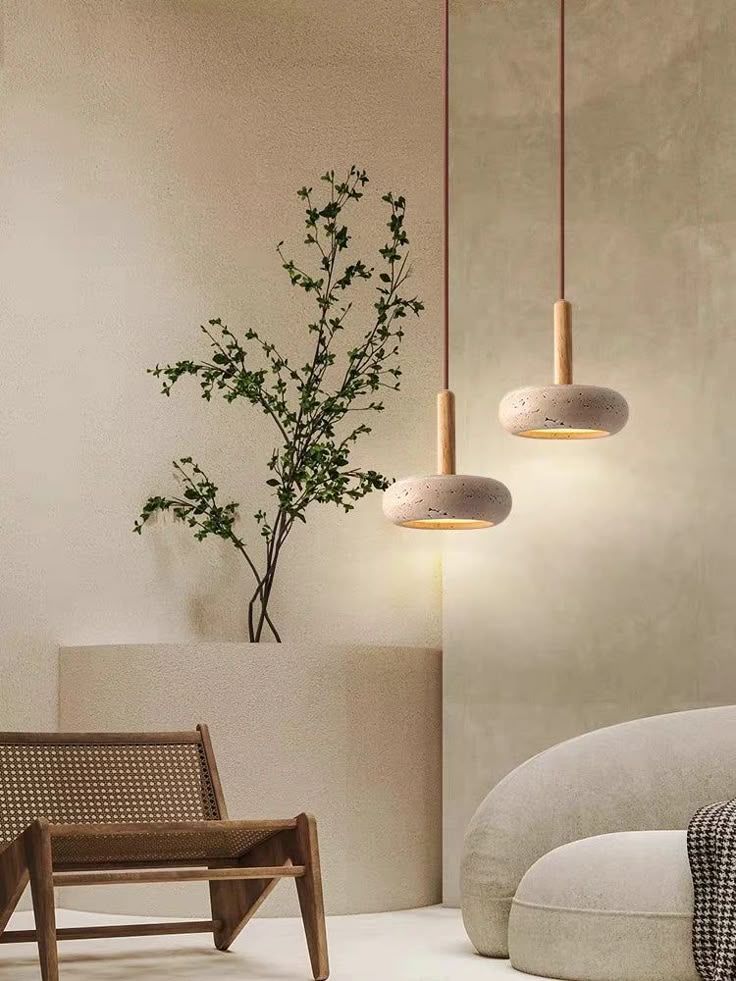 Minimalist living room with beige sofa, wooden chair, pendant lights, and indoor plant for modern home decor.