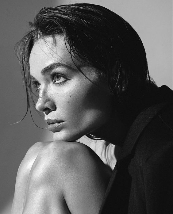 Black and white portrait of a pensive woman with wet hair, gazing thoughtfully, wearing a dark outfit.