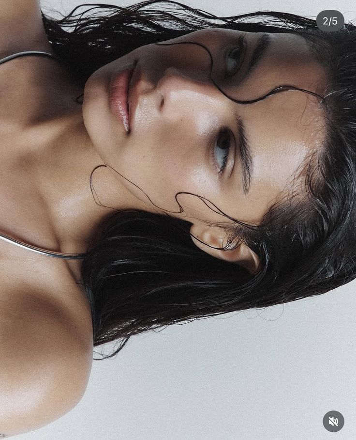 Portrait of a person with wet hair and a neutral expression, showcasing natural beauty and minimalistic style.
