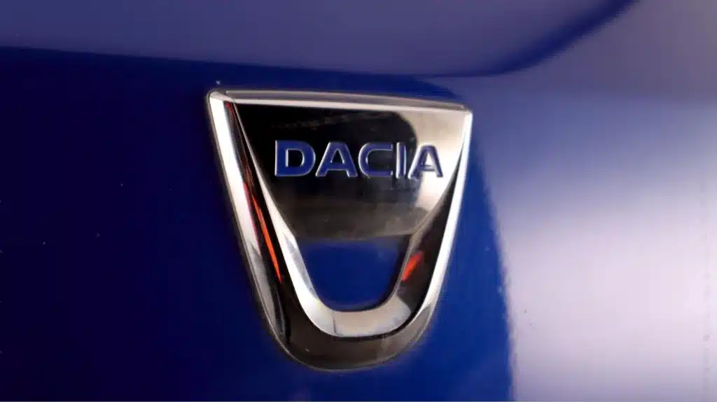 Close-up of Dacia car logo on a blue background, showcasing the brand emblem design.