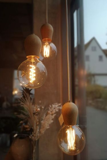 Hanging vintage Edison bulbs with glowing filaments in cozy indoor setting by a window.