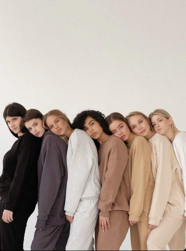 A diverse group of models in neutral, oversized loungewear, leaning in line against a white background.