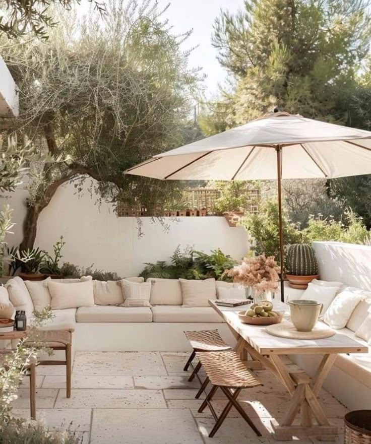 Cozy outdoor patio with seating, dining set, and greenery under a large umbrella for a relaxing, inviting atmosphere.