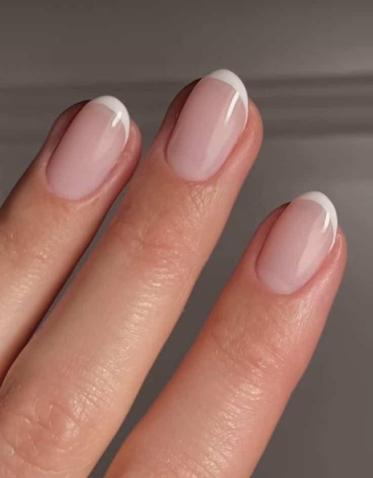 Close-up of fingers featuring a classic French manicure with neatly painted white tips.