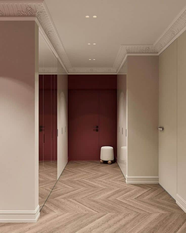 Elegant hallway with herringbone wood floor, modern decor, and red accent door. Minimalist design with soft lighting.