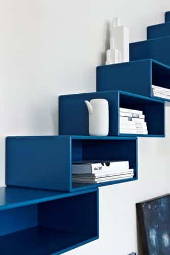 Innovative blue wall-mounted shelves with books and a white vase, showcasing modern interior design.