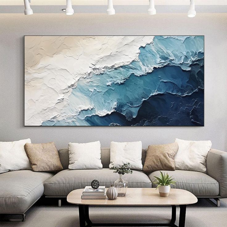 Abstract ocean wave painting in a modern living room with a beige couch and soft lighting.