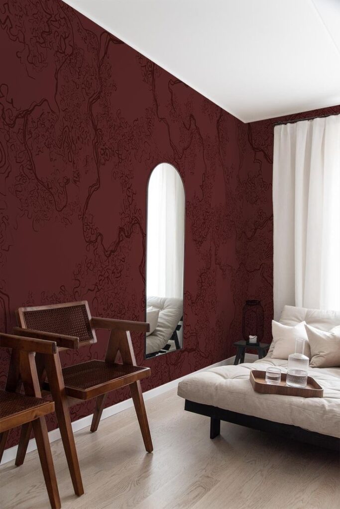 Modern living room with maroon textured wall, oval mirror, wooden chairs, and cozy white sofa.