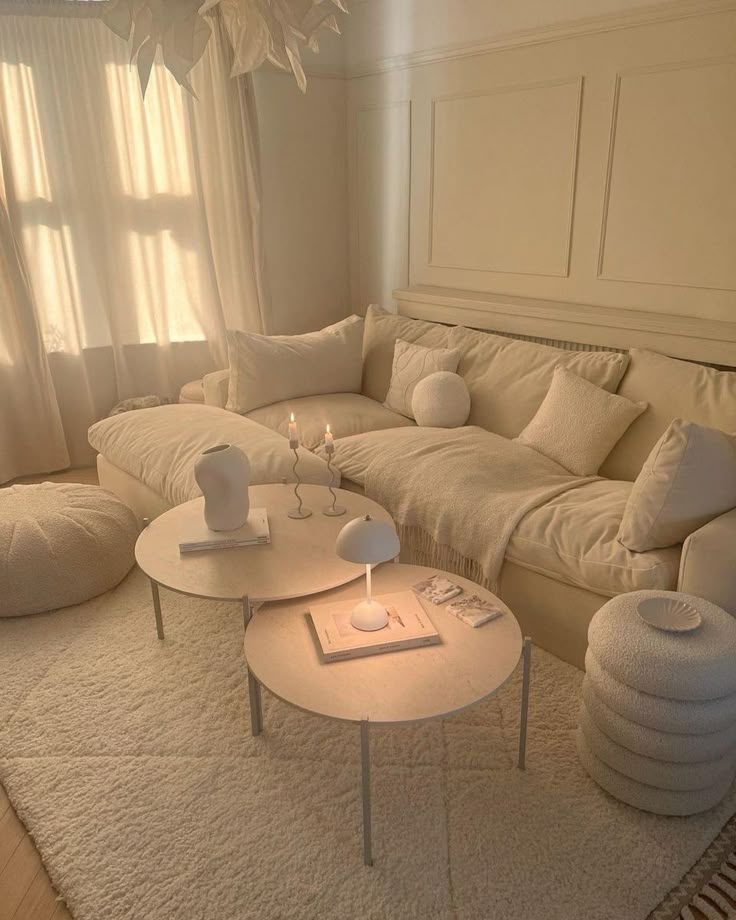 Cozy neutral living room with plush sofa, round tables, soft lighting, and textured decor elements.