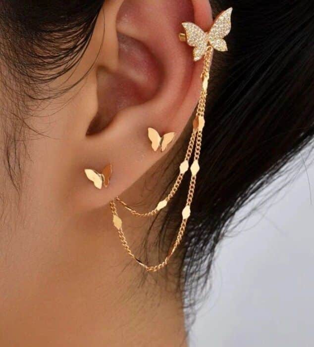 Elegant butterfly gold earring with delicate chains draped gracefully along the ear, showcasing intricate design.