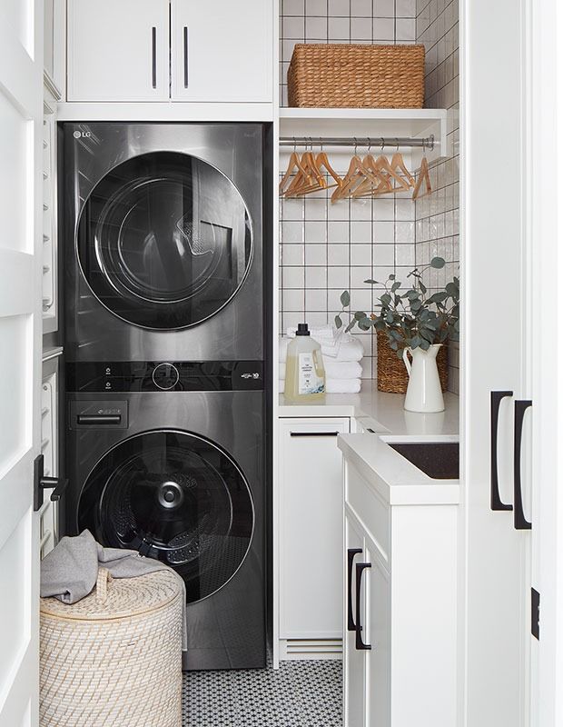 Before After_ Shannon Cooper Transforms a Classic Home In The Beaches For A Young Family Modern laundry room with stacked washer and dryer, wicker basket, shelves with hangers, and eucalyptus in a vase. | Sky Rye Design Modern laundry room with stacked washer and dryer, wicker basket, shelves with hangers, and eucalyptus in a vase.