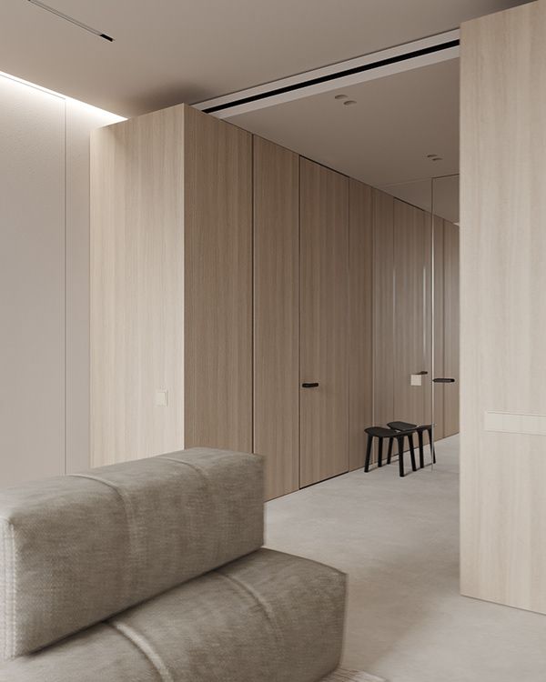Modern minimalist interior with beige walls, a gray sofa, and a black stool. Clean lines and soft lighting create a serene atmosphere.