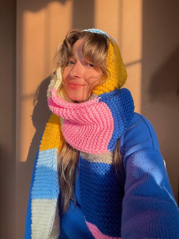Bhava Style Colorful Scarf - Warm Winter Scarf Person smiling in multicolored knit scarf, enjoying sunlight indoors. Cozy and warm winter fashion. | Sky Rye Design Person smiling in multicolored knit scarf, enjoying sunlight indoors. Cozy and warm winter fashion.