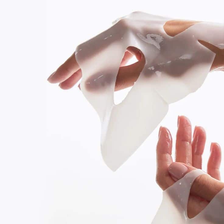 Hands peeling off a translucent sheet mask, showcasing skincare and hydration benefits.