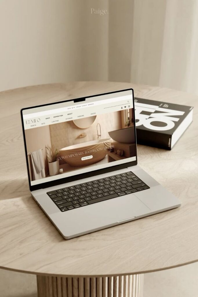 Laptop on a wooden table displaying a website with contemporary bathroom decor.