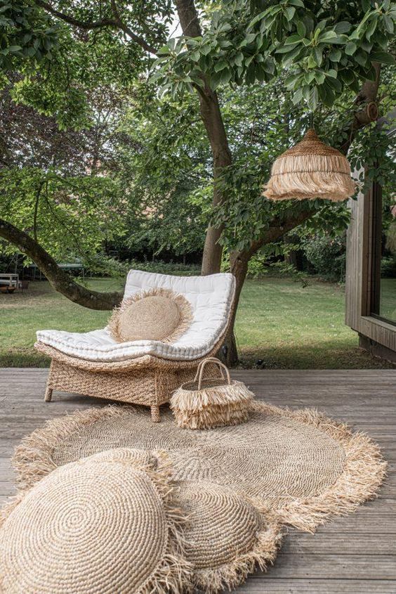 Cozy outdoor patio with wicker chair, natural fiber rug, and greenery for a relaxing garden retreat.