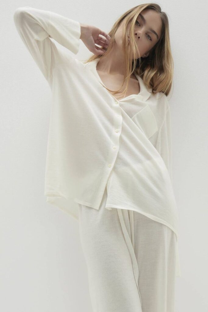 Woman in elegant white loungewear pose against a minimal background, showcasing fashion simplicity and comfort.