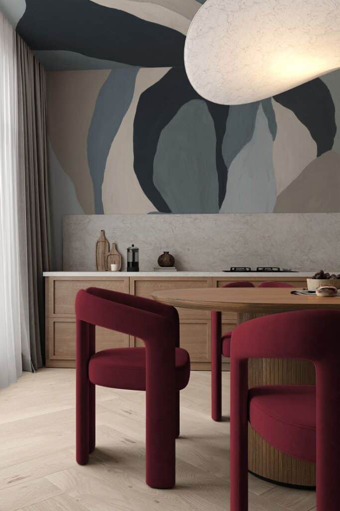 Modern dining room with abstract mural, red chairs, and wooden table. Elegant interior design with curved accents.