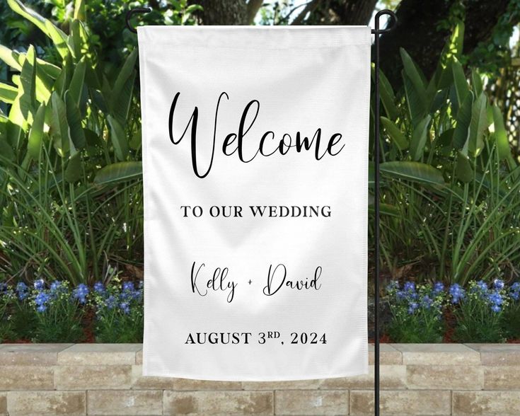 Wedding welcome sign with names Kelly and David, dated August 3, 2024, set in a garden backdrop.