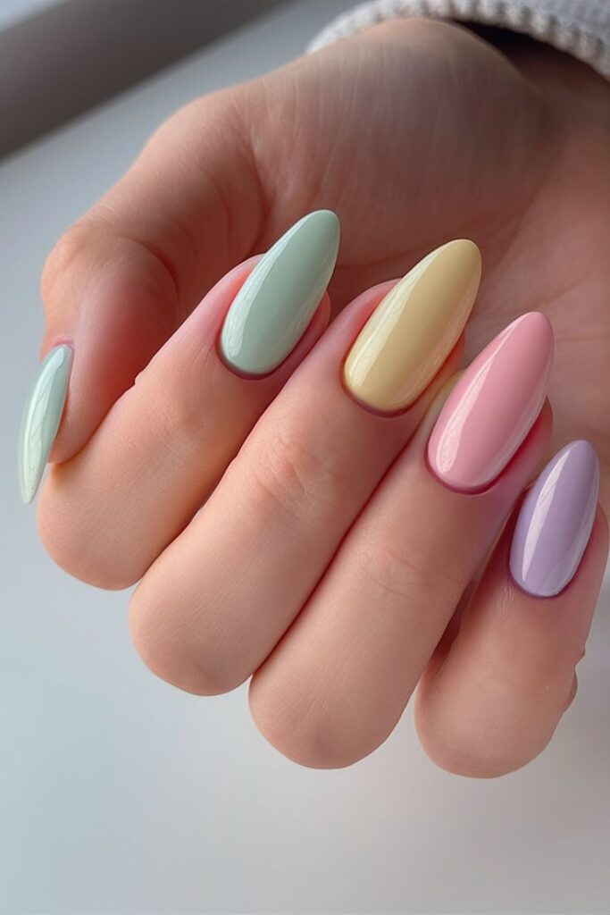 Pastel-colored, long, manicured nails. Mint, yellow, pink, and lavender polish on a hand showing a stylish nail art design.