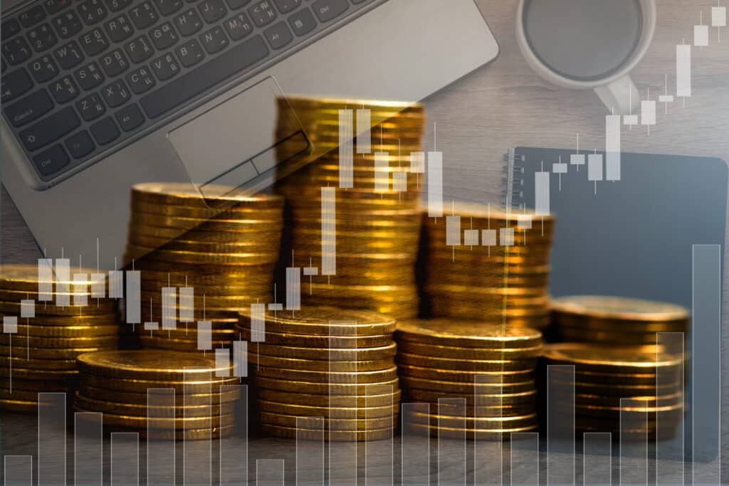 Stacks of gold coins with a stock market graph overlay, showcasing financial growth and investment analysis.