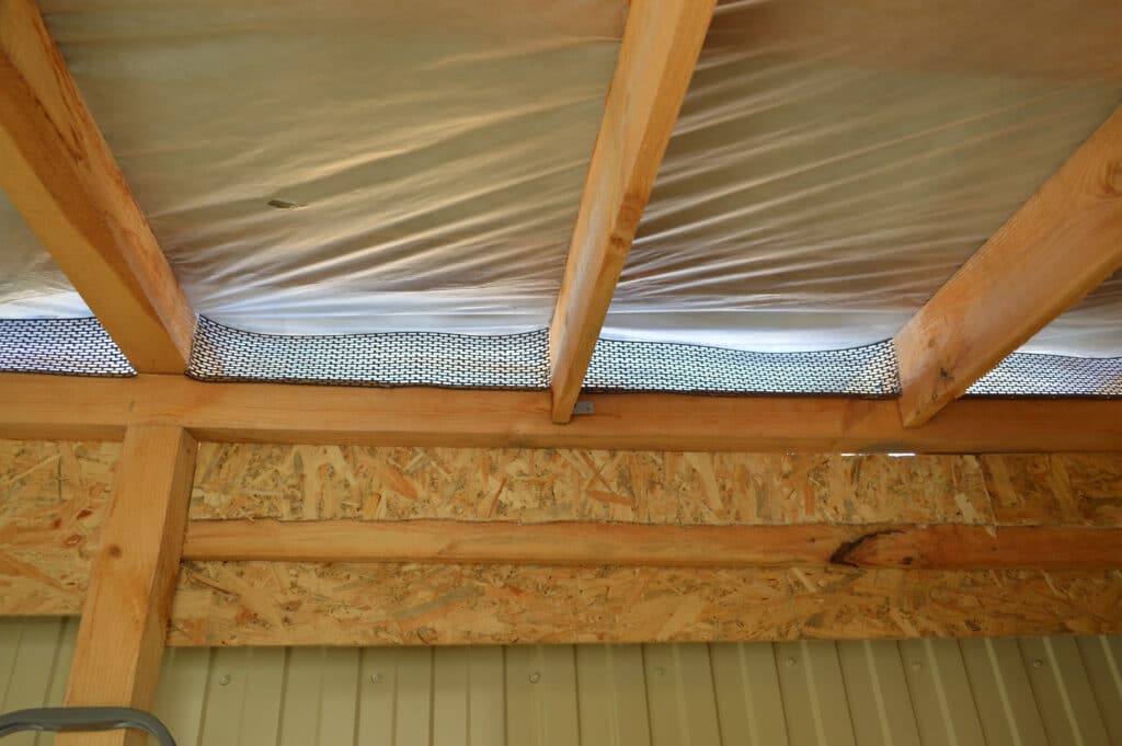 Insulated roof with wooden beams and netting, showcasing construction details for efficient thermal protection.