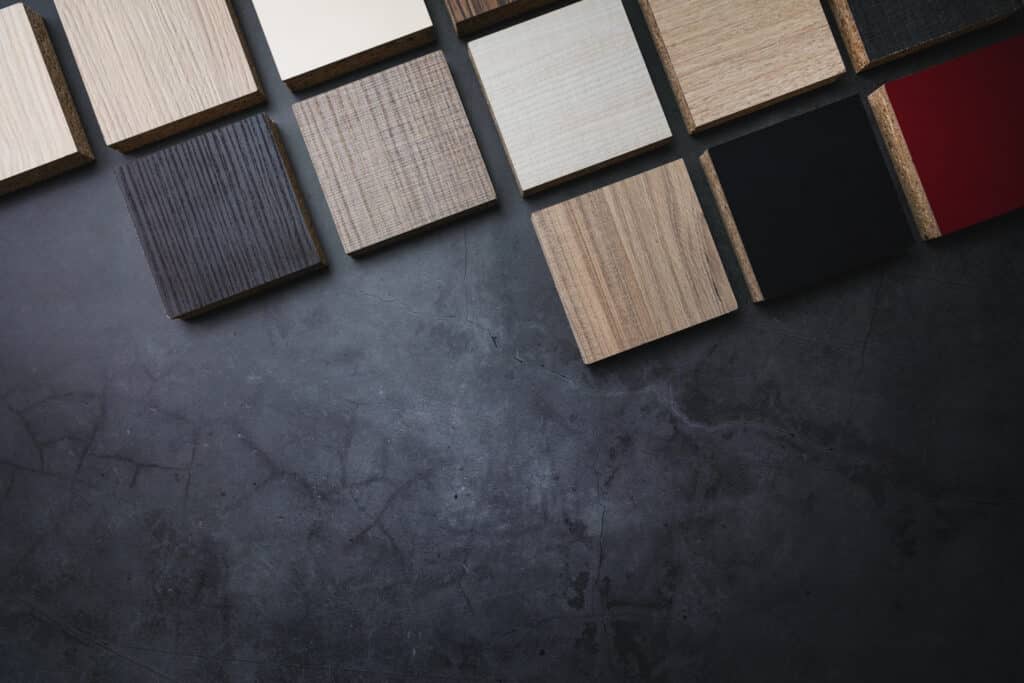 Wood veneer samples on dark textured background, showcasing various colors and finishes for interior design.