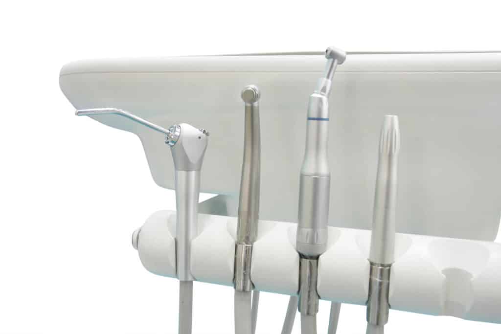 Dentist tools arrangement on a white background, featuring drills and equipment for dental procedures.