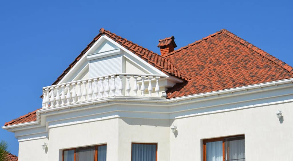 Depositphotos_605782178_XL Red tiled roof house with white balcony against clear blue sky. | Sky Rye Design Red tiled roof house with white balcony against clear blue sky.