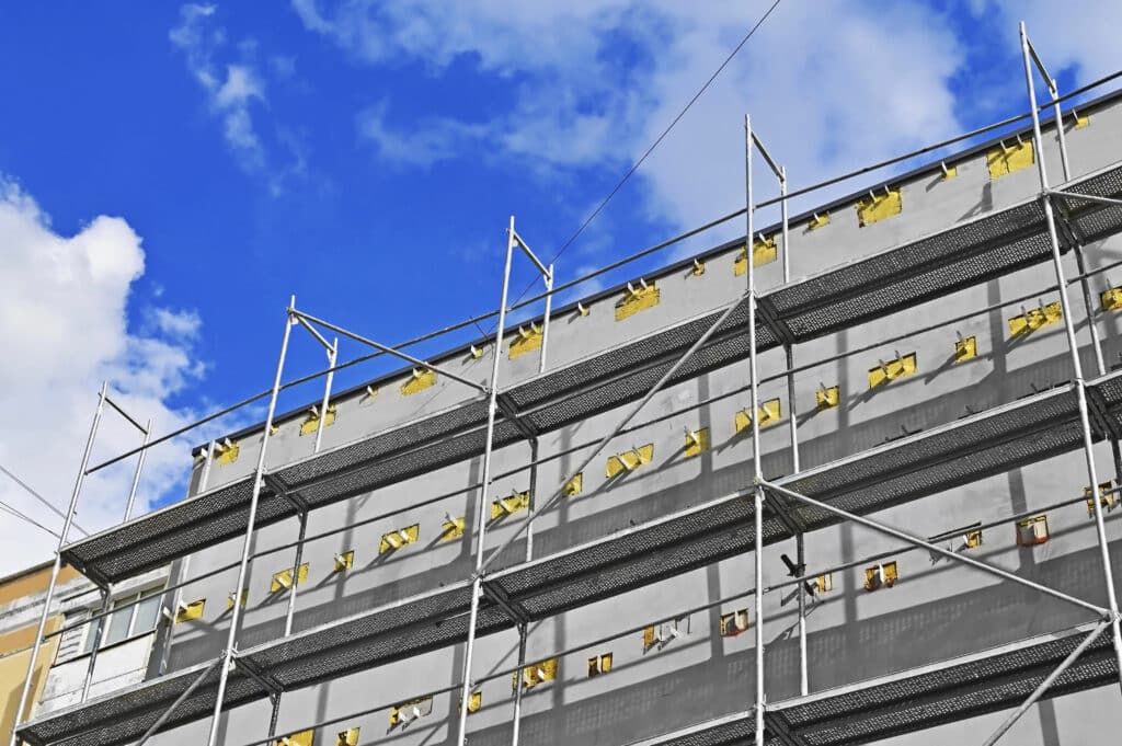 Building under construction with scaffolding against blue sky.