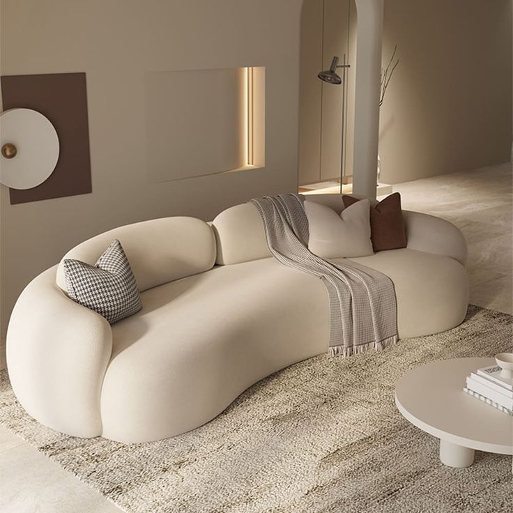 Modern curved sofa with cozy cushions and a throw blanket in a minimalist living room setting.